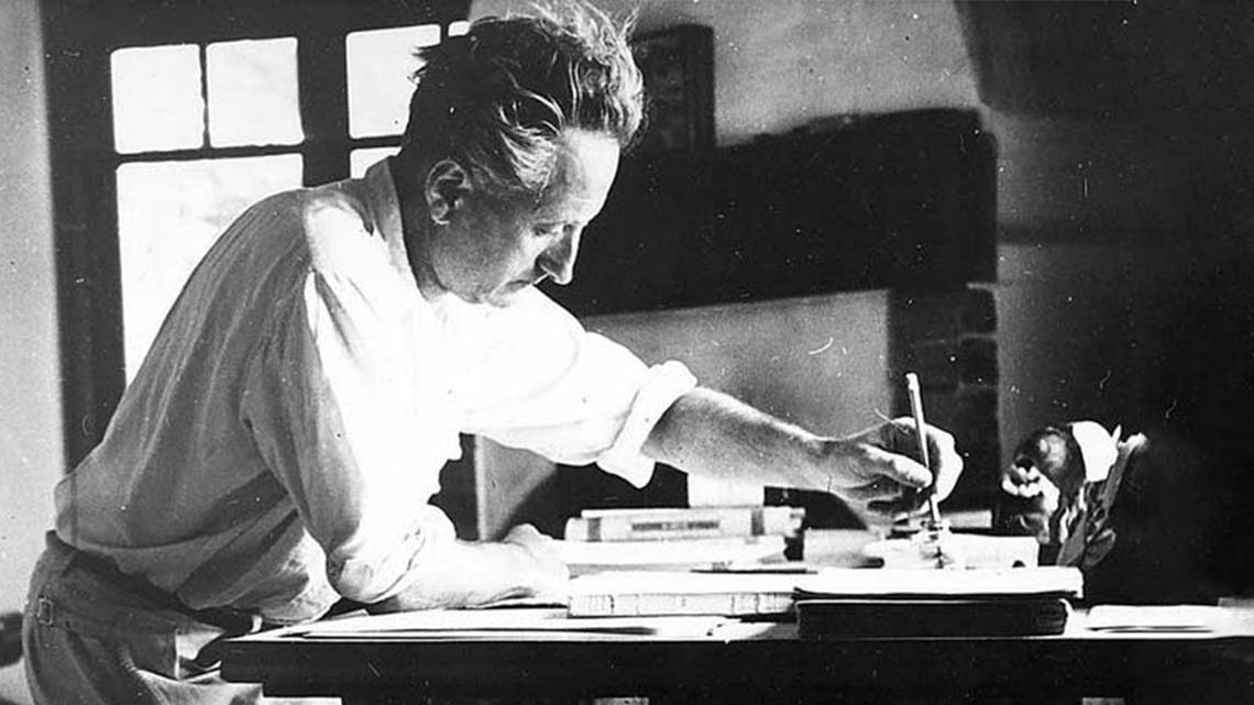 A black & white photo of Jean Giono at his writing desk